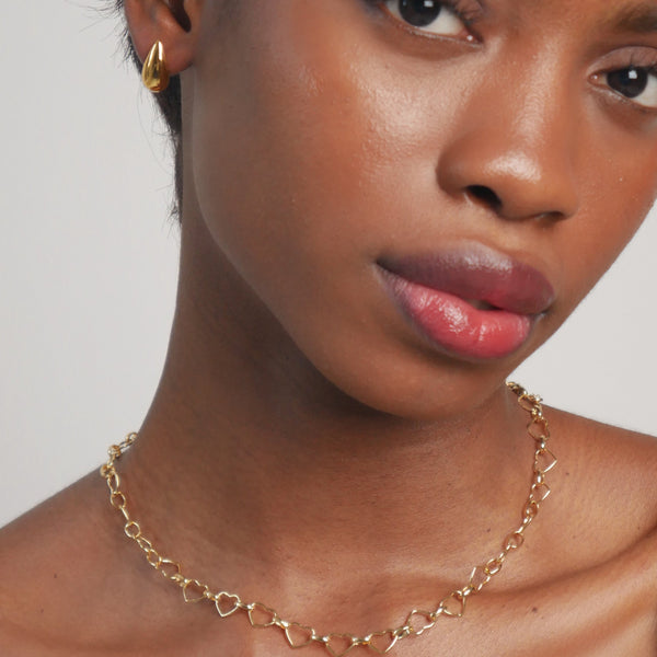 Woman wearing a gold necklace against a neutral background